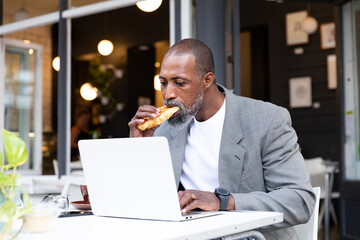 African American man working on his laptop at coffee terrace