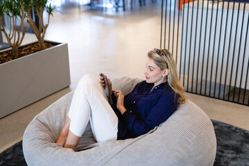 Obraz premium Caucasian woman using a digital tablet in a bean bag