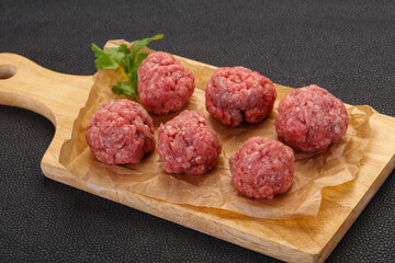 Raw meatball over wooden background