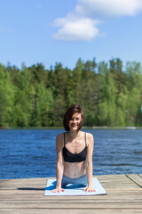 Woman practicing yoga and do exercise, smiling. fitness lifestyle at the outdoors nature background. Sunny day on lake