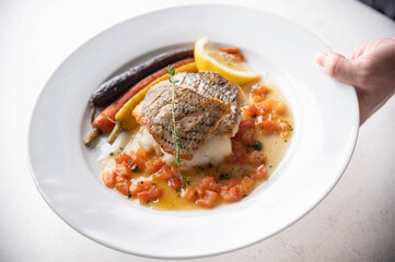 chef serving luxury seabass plate with hand