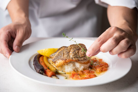 chef garnishing  seabass poele plate