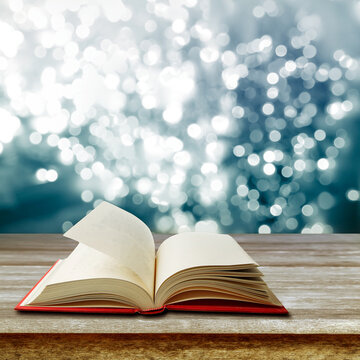 Open book on table in front of blue bokeh background