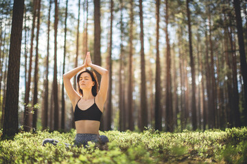Woman practicing yoga in forest with namaste over the head. fitness lifestyle at the outdoors nature background. Sunny day in pine forest. copy space