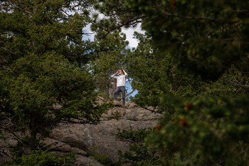 Man standing on a mountain in a clearing of trees.