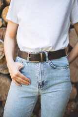 woman wearing jeans, whire tshirt and black leather belt with metal buckle. wardrobe accessory...