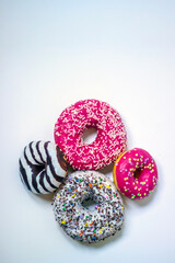 Top view of four donuts on white background. Glazed donuts or doughnuts set - various colors and tastes 3d rendering. Cute, colorful and glossy donuts with glaze and powder.