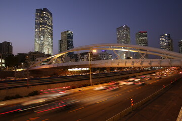 night traffic in Tel Aviv. modern metal bridge in the city in the downtown over the highway and railway. concept of modern engineering construction. slow shutter speed