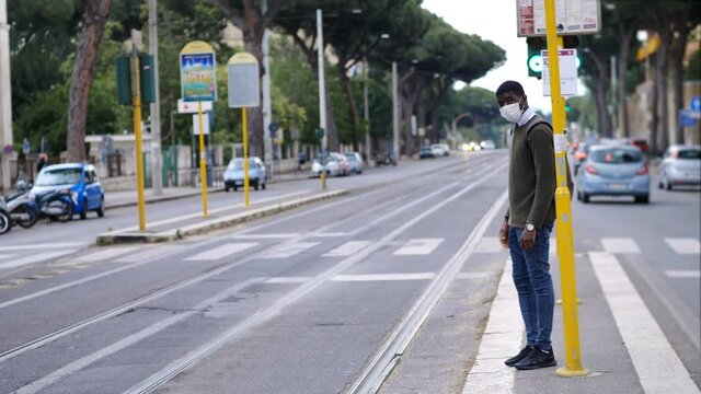 young black man wearing surgical mask waiting for bus - corona virus epidemic