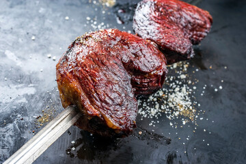 Barbecue dry aged wagyu Brazilian picanha from the sirloin cap of rump beef offered as closeup on a skewer on a rustic old board