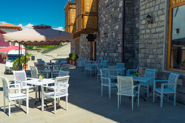 tables of an empty street cafe near an authentic stone wall