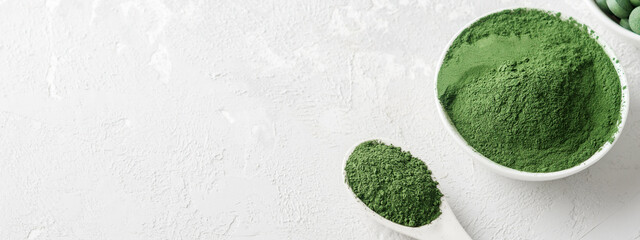 Chlorella or spirulina in the form of tablets and powder on a gray concrete background. - obrazy, fototapety, plakaty