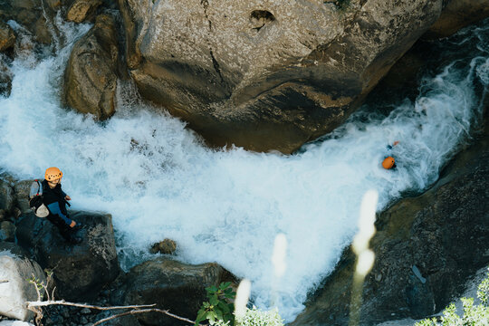 People with wetsuits
and helmet canyoning in a wild river with a lot of water flow
