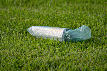 Wrapped newspaper sitting on a green lawn