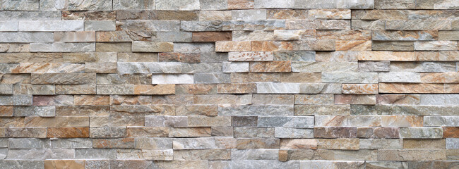 Panorama Detail einer Steinwand aus hellen, groben Verblendsteinen in verschiedenen grauen und...