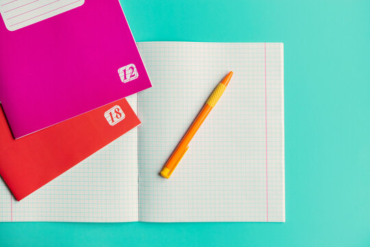 School notebooks on a turquoise background. Open notebook. Pen in the notebook. School accessories. Stationery. Stationery template. A pen. Notebook. Turquoise background.