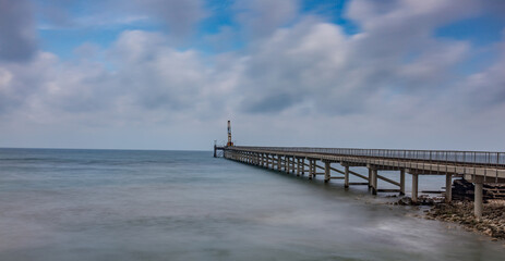 Fototapeta na wymiar A horizontal shot of a wooden deck on a beautiful sandy beach under puffy clouds