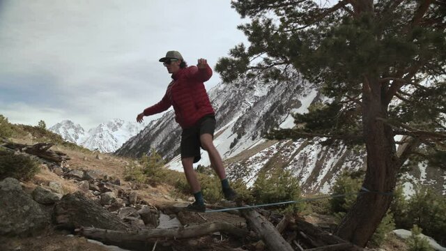 A young man teeters on a slackline in the mountains of the north Caucasus.