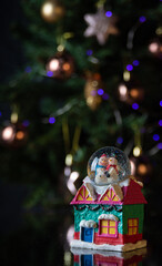 Christmas scene with tree, lights and snow globe. Selective focus on black background.