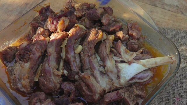 Delicious prepared lamb meat in glass tray is placed on the wooden table outdoors