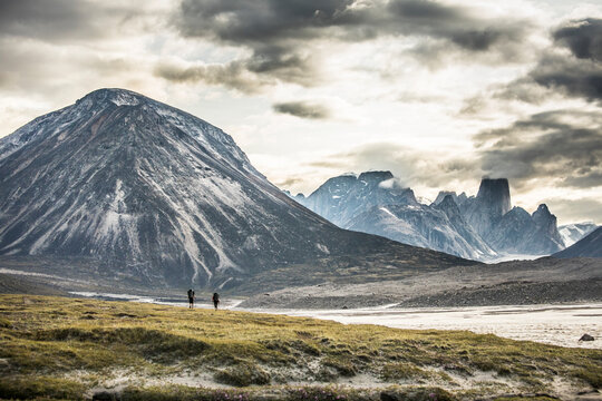 Silhouette of two backpackers hiking through dramatic mountain pass.