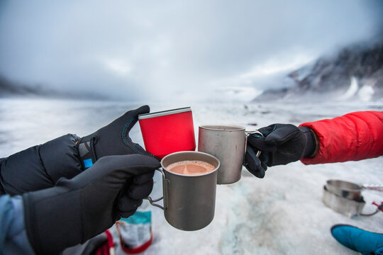 Three mountaineers clink their glasses together after a day of climbin