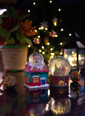 Christmas scene with tree, lights and snow globe. Selective focus on black background.