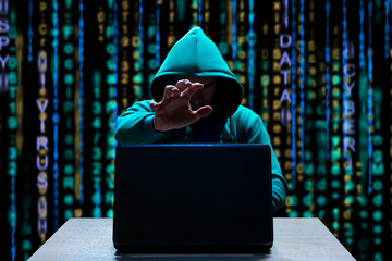 Hooded hacker reaches out to laptop to steal personal information. Cybercrime