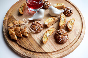 Traditional italian cantuccini cookies with almonds and dried cranberries with a glass of red sweet wine on a wooden background. Home baking concept.