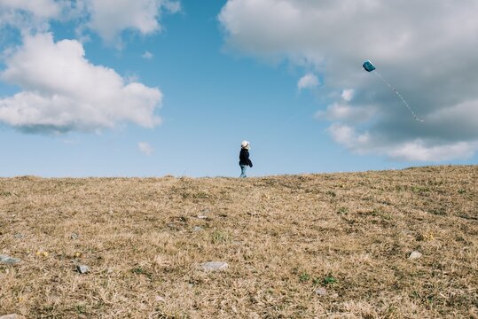 young boy flying a kite on a hill on a sunny day
