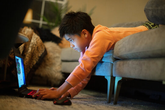 A 12-year old boy in an unusual body position uses a laptop computer
