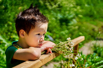 Portrait of sad little boy standing on the bridge at the day time
