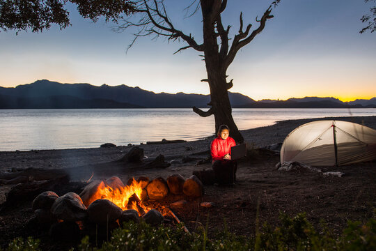 Woman working on laptop at camp at the Nahuel Huapi Lake in Patagonia