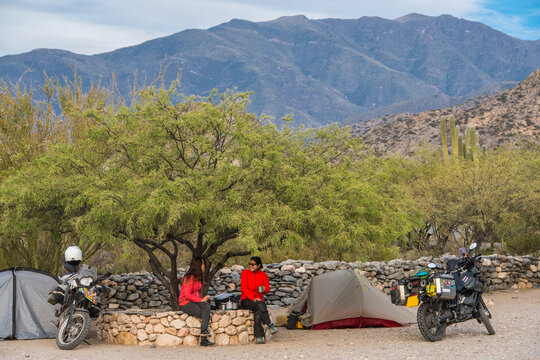 Two women sitting beside motorbike camp at the Ruinas de Quilmes