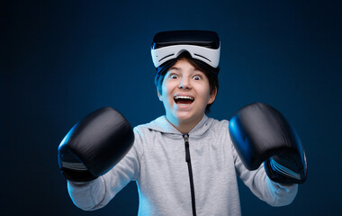 Portrait of young boy in glasses of virtual reality, boxing gloves and hoodie on dark background. Augmented reality, future technology concept. VR. Blue neon light.
