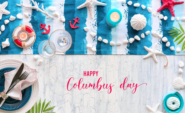 Columbus Day lunch table setting with nautical sea decorations on blue stripy runner, classic blue white plates on rustic table. Flat lay arrangement, panoramic image, text Happy Columbus Day.