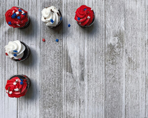 five red and white cupcakes on a white wooden board