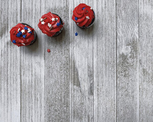 three red cupcakes, muffins, with decorative stars on a white textured wooden board, high-quality photo, free space for text, background for the holiday of Independence Day USA, horizontal