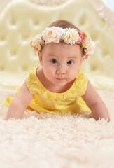 Cute little baby girl in wreath on bed