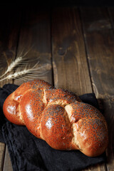 Homemade crusty loave of wheat candy bun with poppy seed on wooden table