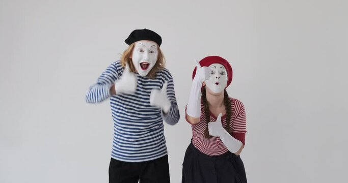 Excited mime artist couple giving thumbs up gesture and celebrating success