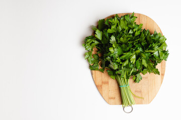 .A bunch of green parsley on a bamboo cutting board on a white salted background.