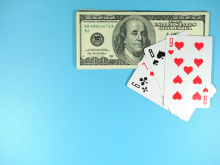 one hundred dollar banknotes and a gaming cards on a blue background, risk and luck, copy space