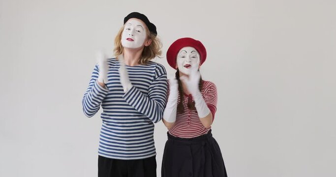 Excited mime artist couple clapping hands and congratulating over white background