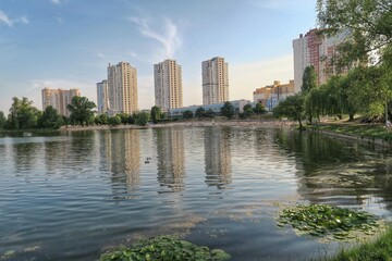 Fototapeta premium Kyiv/Kiev skyline at the peaceful river. Soviet looking buildings, river reflection of the buildings. Kyiv Ukraine.