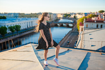 Cute girl on rooftop enjoying with view of beautiful sunset in Sankt Petersburg in Russia