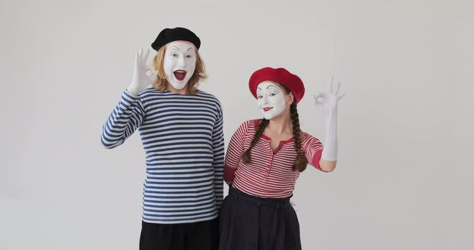 Happy mime artist couple gesturing ok sign and giving thumbs up gesture
