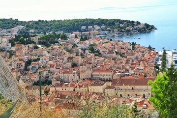 Fototapeta premium Hvar, Croatian island. High angle, panorama view of the old town, partial view of the sea. Terracotta coloured rooftops. 