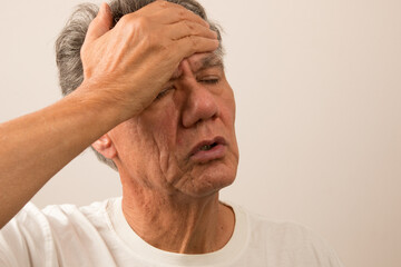 Senior Man in pain with Headache with hand on forehead