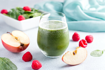 Glass with green smoothie with reusable drinking straws with spinach, raspberry and apple on...